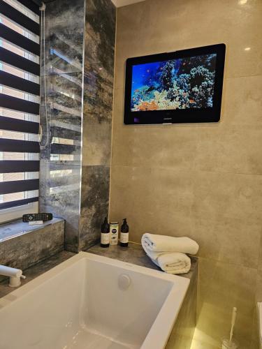 a bathroom with a tub and a tv on the wall at Galaxy Apartments 2 in Słupsk