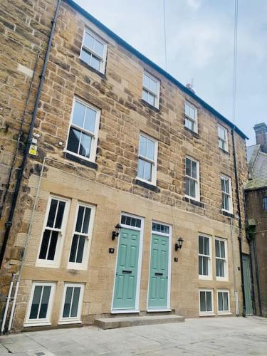 a brick building with green doors and windows at Luxury Retro 4 Bed Town House in heart of Alnwick in Alnwick