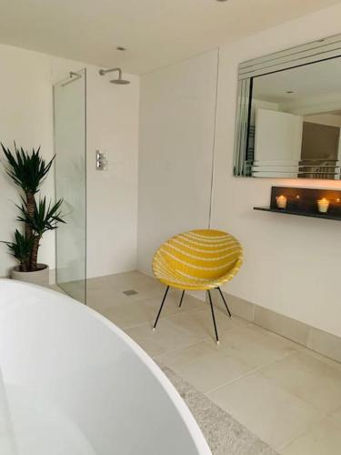 a yellow chair in a bathroom with a shower at Luxury Retro 4 Bed Town House in heart of Alnwick in Alnwick