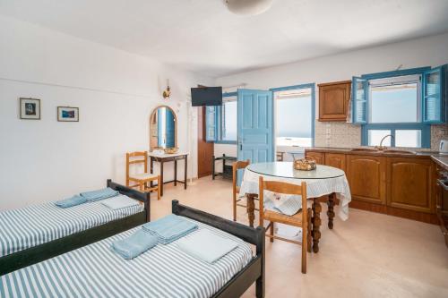 a room with two beds and a table and a kitchen at Alcyone in Serifos Chora