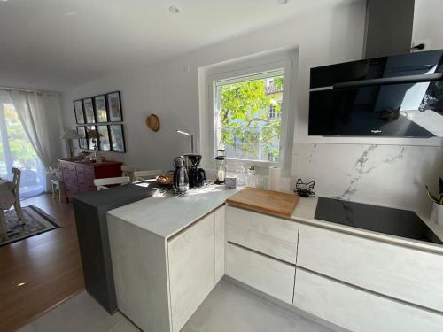 a kitchen with white cabinets and a large window at Gite-le-7 in Brive-la-Gaillarde