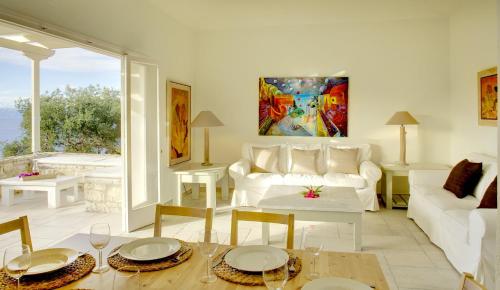 Villa Flora في Oziás: غرفة معيشة مع أريكة بيضاء وطاولة