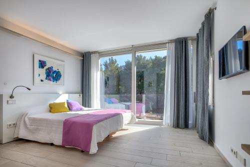 - une chambre avec un lit et une grande fenêtre dans l'établissement Villa LEsplendor, à Cala Sant Vicenç