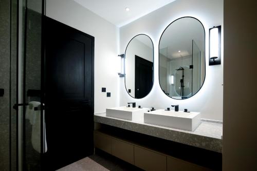 a bathroom with two sinks and two mirrors at Riverfront Apartments Vientiane in Vientiane