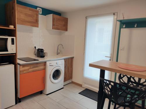 uma cozinha com uma máquina de lavar roupa e uma mesa em Studio spacieux aux portes de la Camargue em Beauvoisin