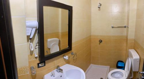 a bathroom with a sink and a toilet and a mirror at AL Hotel in Vlorë