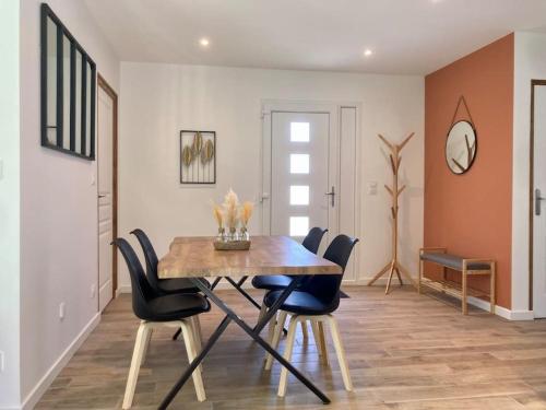 uma sala de jantar com uma mesa de madeira e cadeiras em Maison neuve à deux pas du Mont em Beauvoir