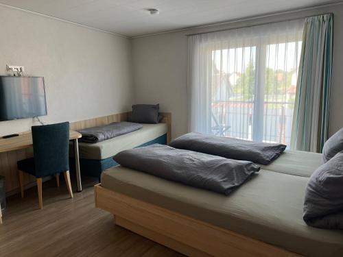 um quarto com 2 camas, uma secretária e uma janela em Hotel Restaurant Bürgerstuben em Altenstadt