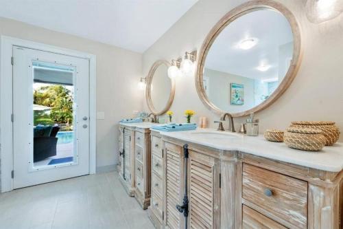 a bathroom with two sinks and a large mirror at Waterfront Oasis w/ Pool Minutes to Downtown! in Boynton Beach