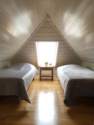 two beds in a attic room with a window at Korshamn Rorbuer in Lyngdal