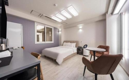 um quarto de hotel com uma cama, uma mesa e cadeiras em Ballantine Business Hotel em Gwangju