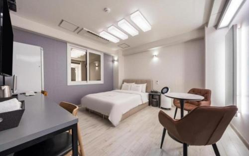 a hotel room with a bed and a table and chairs at Ballantine Business Hotel in Gwangju