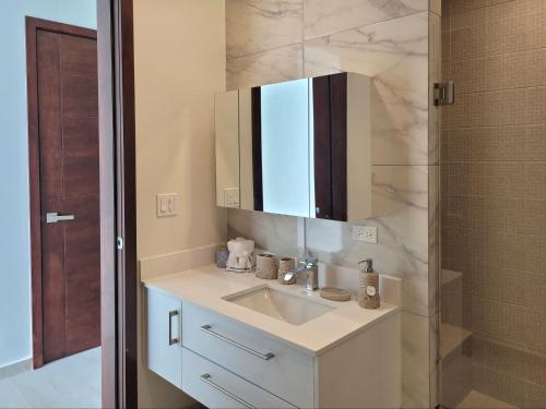 a white bathroom with a sink and a mirror at Beachfront Luxury Seaside Condo + Pool & Jacuzzi in Rosarito