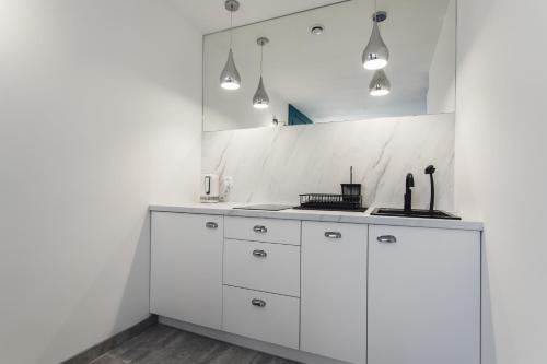 a white kitchen with a sink and a mirror at Livin Łeba in Łeba