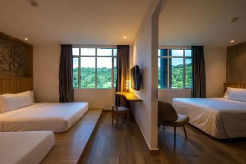 a hotel room with two beds and a desk at The Bayou Hotel Langkawi in Pantai Cenang