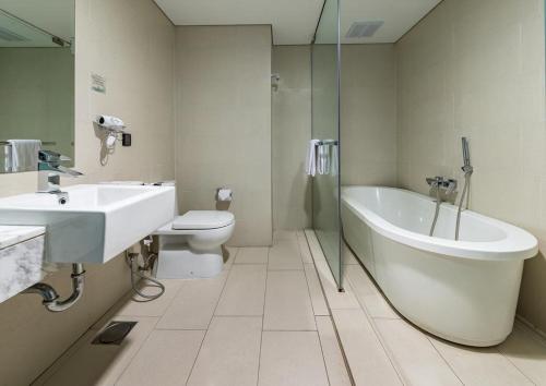 a bathroom with a tub and a toilet and a sink at The Straits Hotel & Suites in Malacca