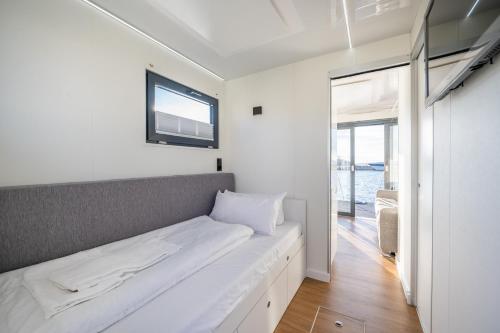 a white bedroom with a bed with a window at Marina Martinshafen in Sassnitz