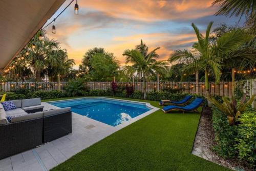 a backyard with a pool and a lawn with palm trees at Modern Comfortable Stay!Sleeps 8! in West Palm Beach