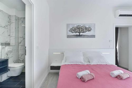 1 dormitorio con 1 cama rosa y 2 toallas en Luxury Stone Villa BANOVI with heated pool, en Vinjerac