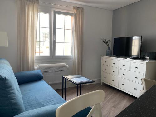 a living room with a blue couch and a tv at Deluxe City Centre Two Bedroom with Private Balcony - Grand Central House in Gibraltar