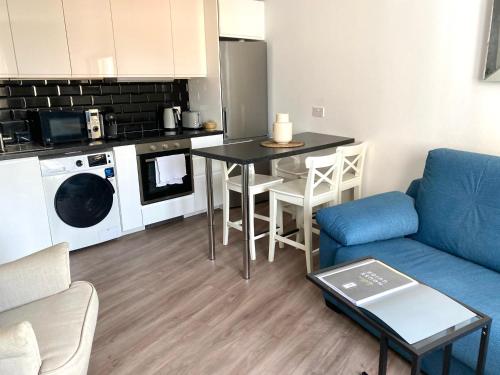 a living room with a blue couch and a kitchen at Deluxe City Centre Two Bedroom with Private Balcony - Grand Central House in Gibraltar