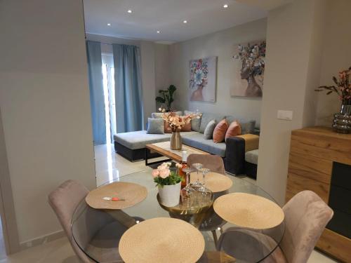 uma sala de estar com uma mesa de vidro e cadeiras em AGORA luxury APARTMENT 3 em Loutraki