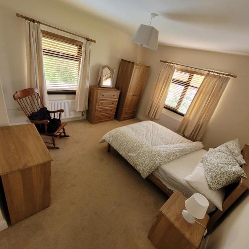 een slaapkamer met een bed, een dressoir en 2 ramen bij Granny O's in Killen
