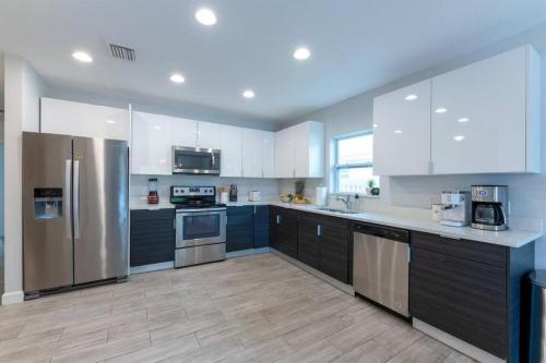 a kitchen with white cabinets and stainless steel appliances at Modern Comfortable Stay!Sleeps 8! in West Palm Beach