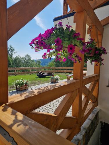 a porch with flowers hanging from a wooden fence at Dusznickie Apartamenty z widokiem in Duszniki Zdrój