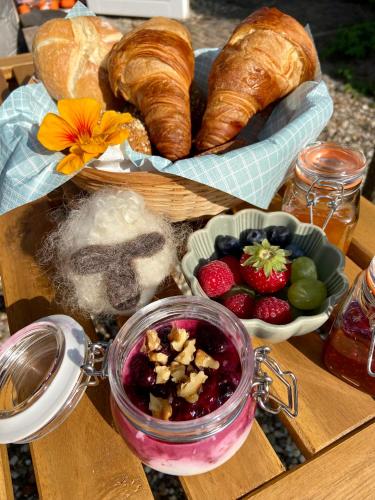 a table with a tray of bread and a bowl of fruit at Huisje aan ‘t Hof in Bronkhorst