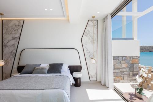 a bedroom with a bed and a large window at Naiades Boutique Hotel - Adults Only in Elounda