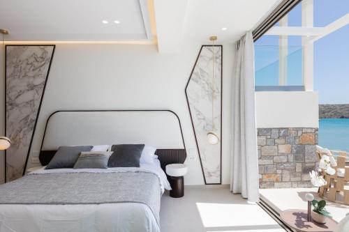 1 dormitorio con cama y ventana grande en Naiades Boutique Hotel - Adults Only, en Elounda