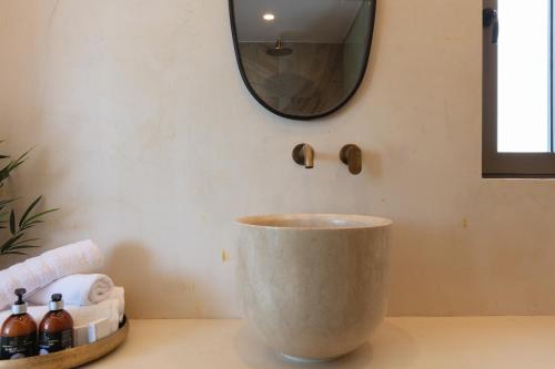 a bathroom with a large concrete bowl on a counter with a mirror at Naiades Boutique Hotel - Adults Only in Elounda