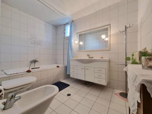 a white tiled bathroom with a sink and a tub at Heraklion flat , near the aiport in Heraklio
