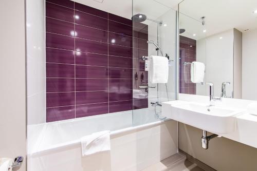 y baño con lavabo y ducha con azulejos morados. en Premier Inn Essen City Centre, en Essen