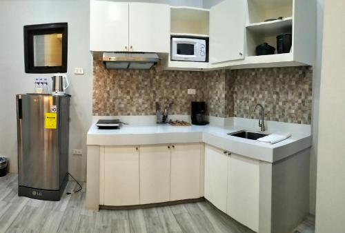 a kitchen with white cabinets and a stainless steel refrigerator at Dachannry's Place Hotel in Cagayan de Oro