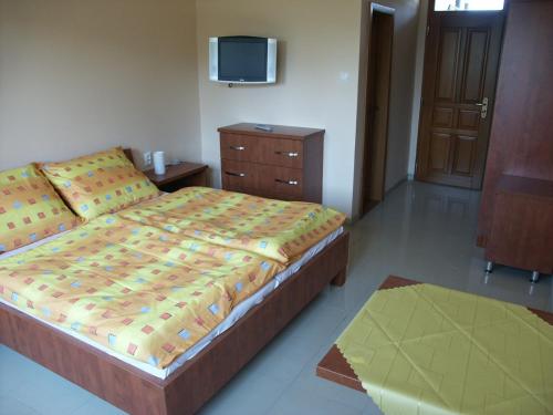- une chambre avec un lit et une télévision murale dans l'établissement Penzion Karen, à Podhájska