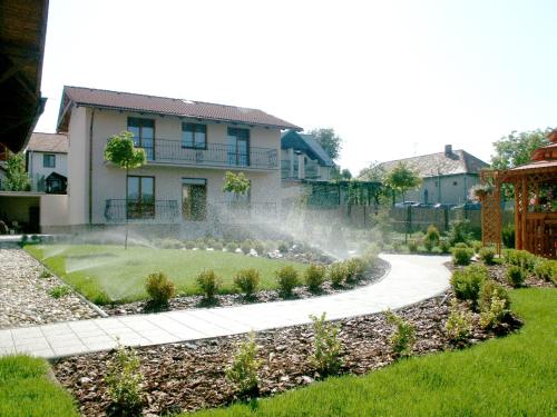 a garden in front of a house with a fountain at Penzion Karen in Podhájska