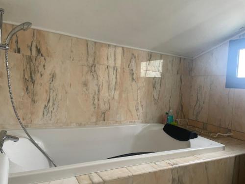 e bagno con vasca e parete in marmo. di Casa Bohème a Santa Susanna