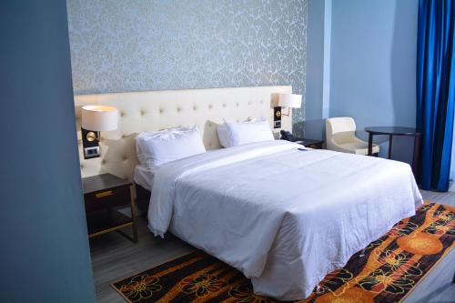 a bedroom with a bed with a white bedspread and pillows at Djeuga Palace Hotel in Yaoundé