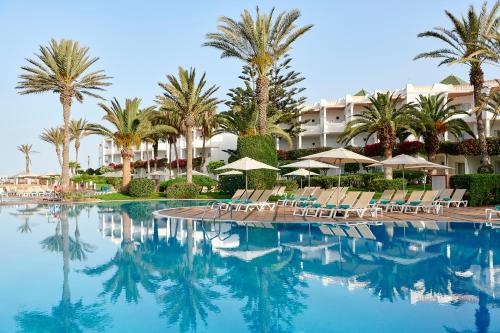 basen z krzesłami i palmami oraz hotel w obiekcie Iberostar Founty Beach All Inclusive w mieście Agadir