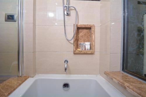 a white bath tub with a shower and a sink at Djeuga Palace Hotel in Yaoundé