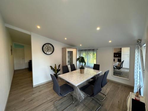 a dining room with a table and chairs and a clock at Beau F4 dans un écrin de verdure in Vernéville