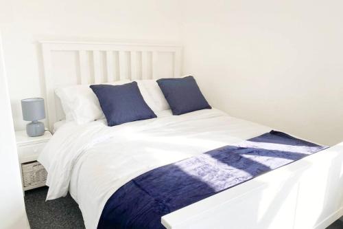 Cama blanca con sábanas y almohadas azules y blancas en Bristol House FREE Parking & Airport & M1 & Contractor, en Luton