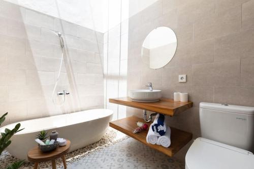 ein Badezimmer mit einer Badewanne, einem Waschbecken und einem WC in der Unterkunft The R Villa Kaba - incl. Motorbikes in Seminyak