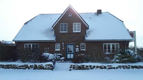 ein rotes Backsteinhaus mit einem schneebedeckten Dach in der Unterkunft Landtraum in Oevenum