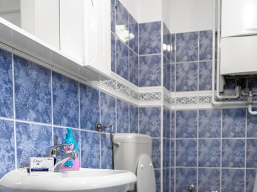 Un baño con azulejos azules, inodoro y lavabo. en Apartmani BA, en Sarajevo