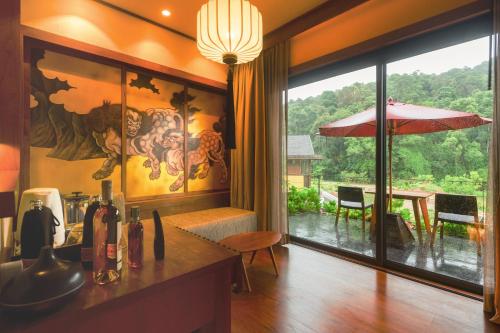 a kitchen with a view of a table with an umbrella at Onsen at Moncham in Mae Rim