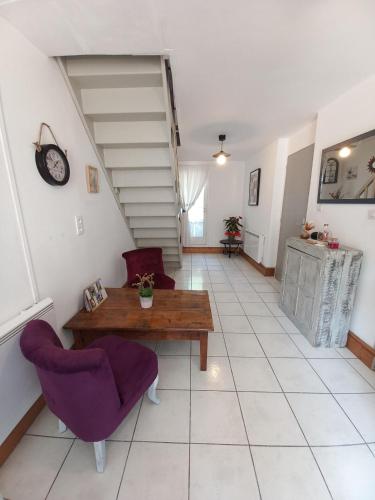 a living room with a table and purple chairs at Auprès du Lavoir in Remigny