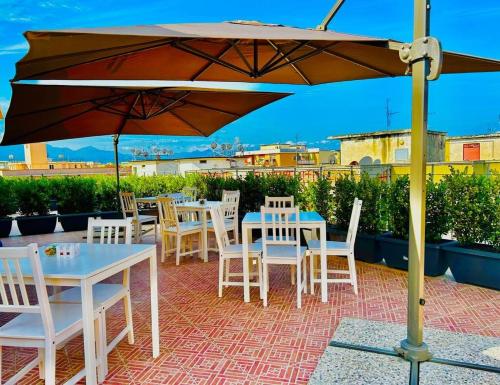 un patio con mesas, sillas y una sombrilla en Aqua B&B - Rooms and Apartments en Milazzo